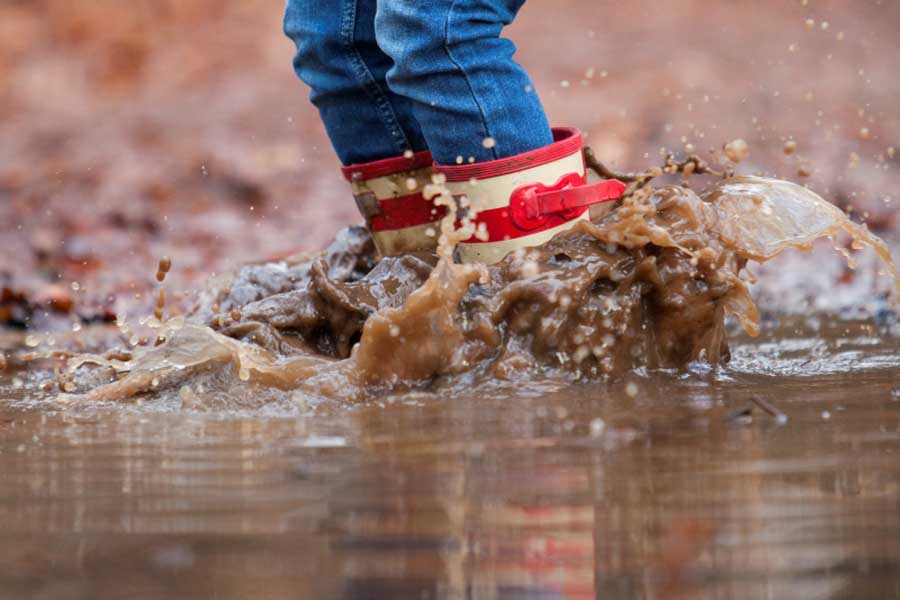 Kinderlaarzen springen in modderplas