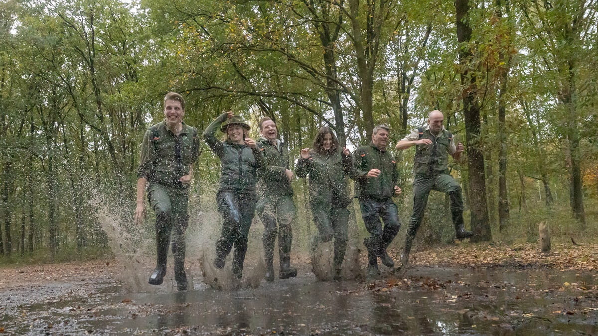 Groep boswachters springt in een plas