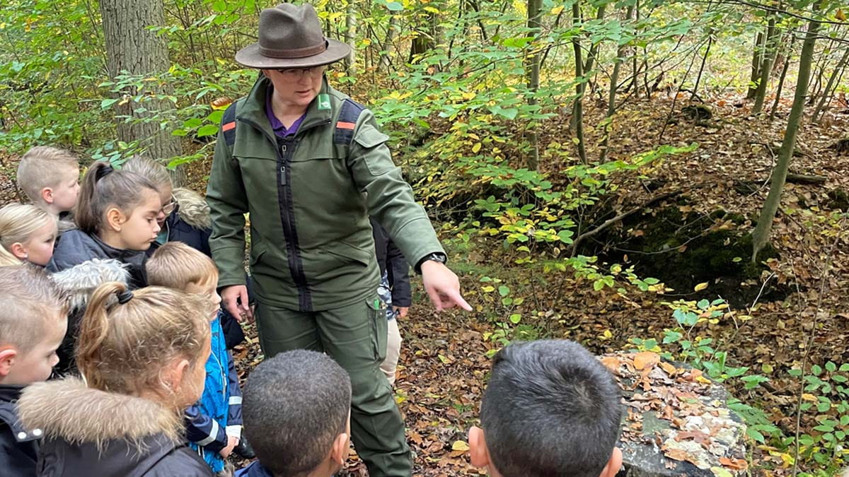 Boswachter legt iets uit aan kinderen in het bos